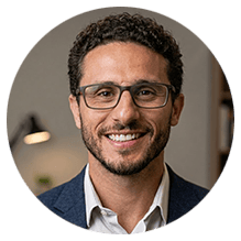 Homem sorrindo de óculos em escritório moderno