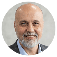 Homem careca sorrindo com barba grisalha em retrato profissional
