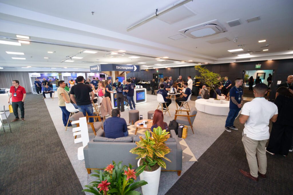 Participantes conversam em estandes de evento de tecnologia